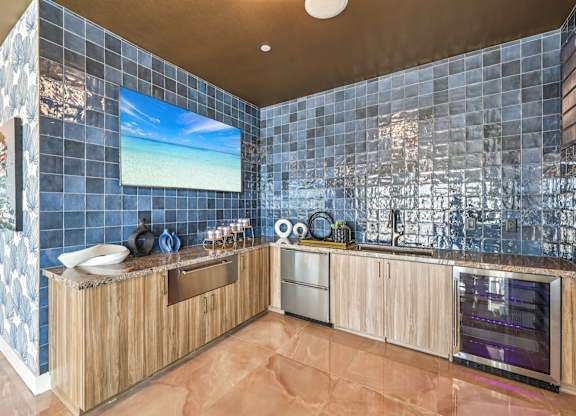 A kitchen with a blue tiled wall and wooden cabinets.at Fora Apartments, Las Vegas Nevada