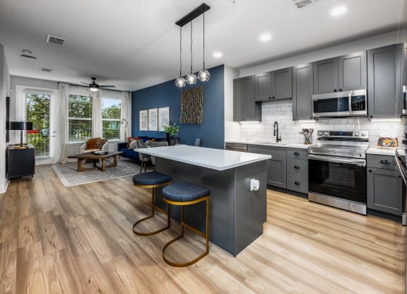 a kitchen and living room with a large island with three stools at The Alibi at Lake Lilly, Florida