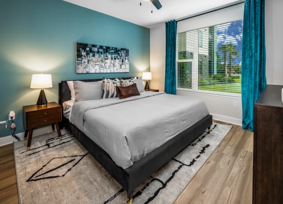 a bedroom with a bed and a large window with blue curtains at The Alibi at Lake Lilly, Ocoee, FL