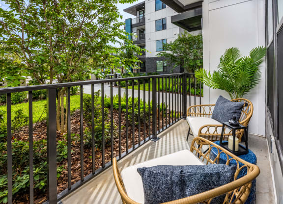 a balcony with two chairs and a table and some plants at The Alibi at Lake Lilly, Ocoee, FL