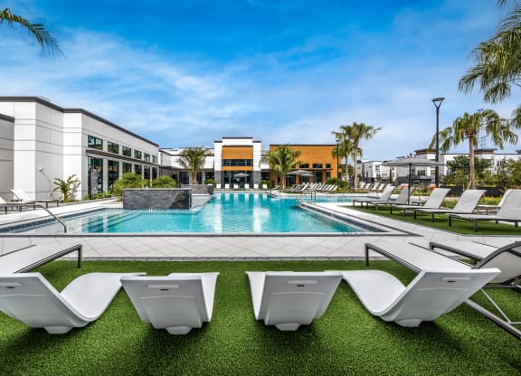 a swimming pool with white chairs and a building in the background at The Alibi at Lake Lilly, Ocoee, FL