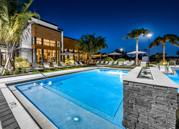 a swimming pool in front of a hotel at night