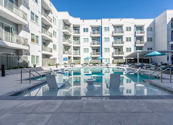 A large pool surrounded by apartment buildings with a blue sky in the background.