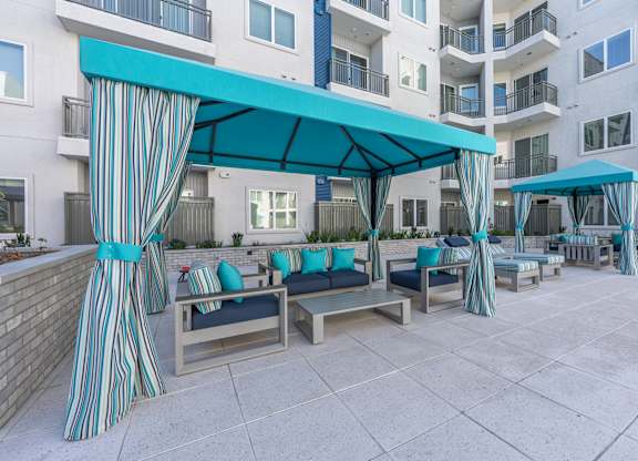 A patio area with a striped canopy and blue cushions.