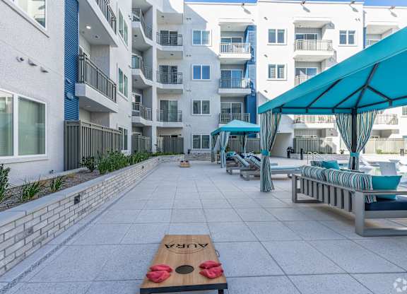A wooden table with a red cloth and a pair of sunglasses on it is in the middle of a courtyard.