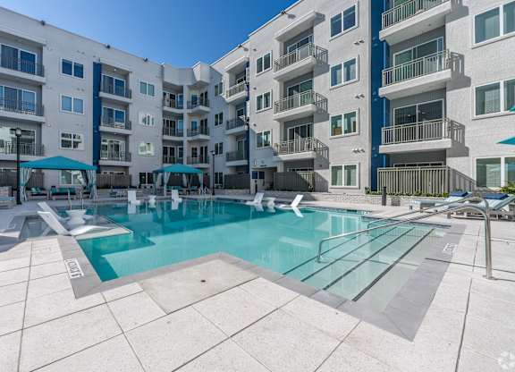A large swimming pool in front of apartment buildings.