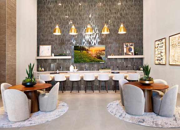 a dining room with white chairs and tables and a large mirror at Aura Vegas Apartments, Nevada