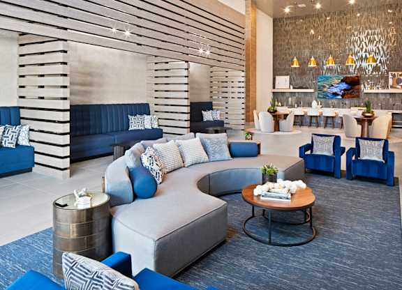 a lobby with blue chairs and couches and a coffee table at Aura Vegas Apartments, Las Vegas, NV