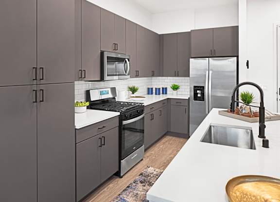 a modern kitchen with stainless steel appliances and white counter tops at Aura Vegas Apartments, Las Vegas, NV 89103