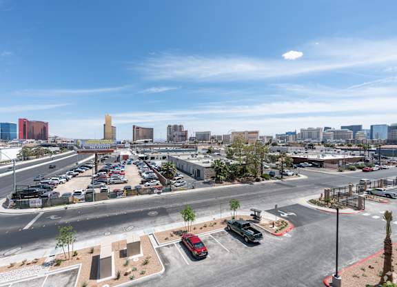 A parking lot with cars and a road in front of a city skyline.