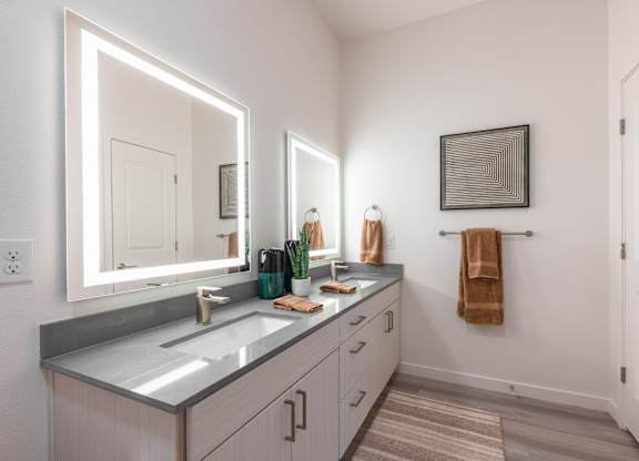 A bathroom with a large mirror, a sink, and a towel hanging on the wall.