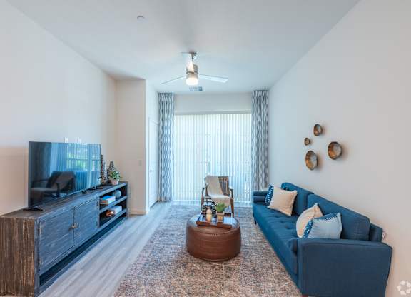 A living room with a blue couch, a wooden cabinet, and a television.