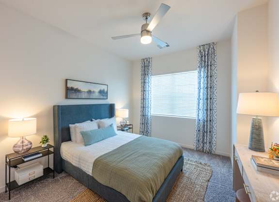 A bedroom with a bed, nightstands, and a ceiling fan.