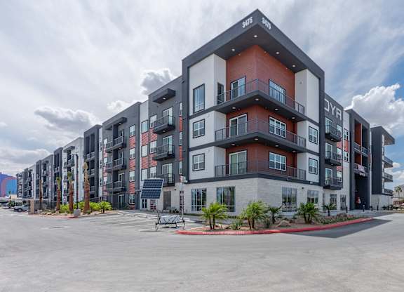 A modern apartment complex with a parking lot in front.