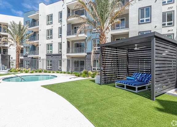 A modern apartment complex with a pool and a sun lounger.