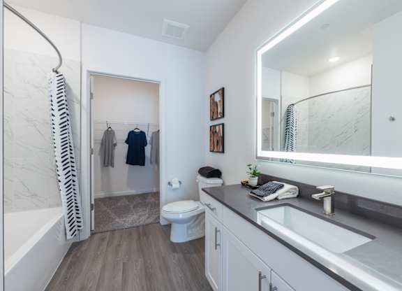 A bathroom with a toilet, sink, and a mirror.