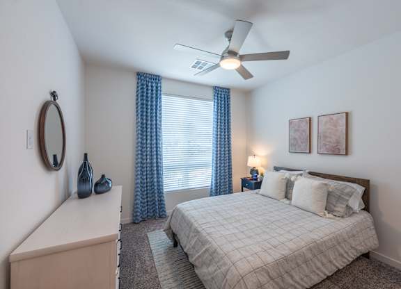 A bedroom with a bed, nightstand, and window with curtains.