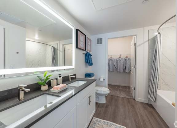 A bathroom with a large mirror, a sink, and a toilet.