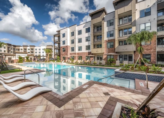 a swimming pool at an apartment building with a pool and lounge chairs at The Haven at Lake Britt Apartments, Winter Garden, 34787
