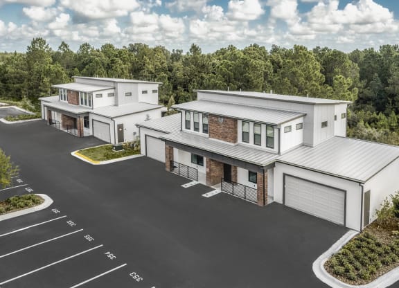 an aerial view of three houses with a parking lot and trees at The Haven at Lake Britt Apartments, Winter Garden, FL 34787