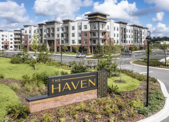 an apartment building with a sign that reads the haven in front of a parking lot at The Haven at Lake Britt Apartments, Florida, 34787