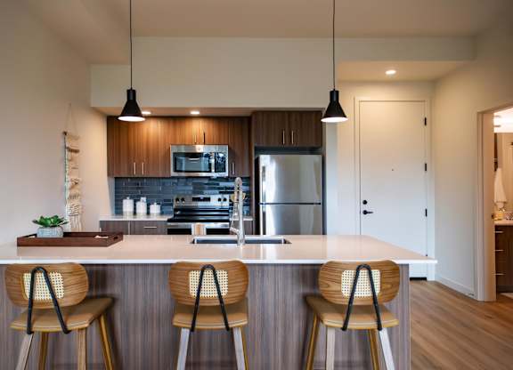 Kitchen with white island and wood bar stools at Montage Apartments, Tigard, OR 97223