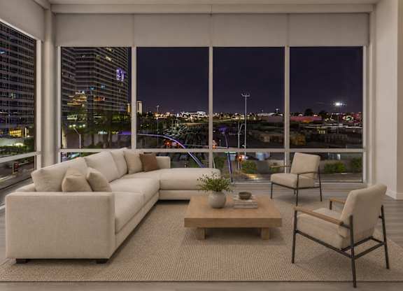 A modern living room with a large window overlooking the city at night.