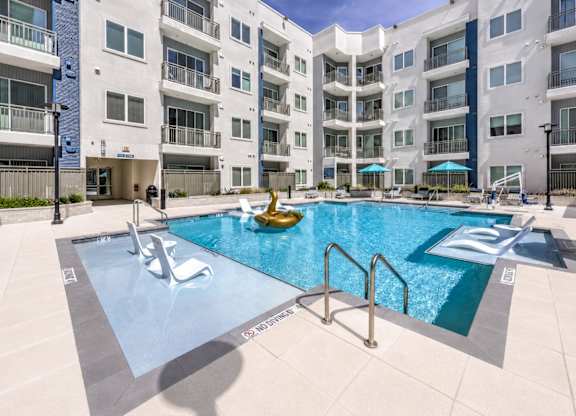 A large swimming pool in front of apartment buildings.