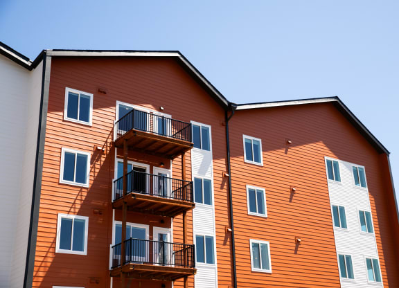 a large building with balconies and a blue sky at The Mill on Maple Apartments, Oregon