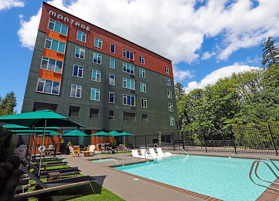 Outdoor pool with lounge chairs and umbrellas at Montage Apartments, Tigard