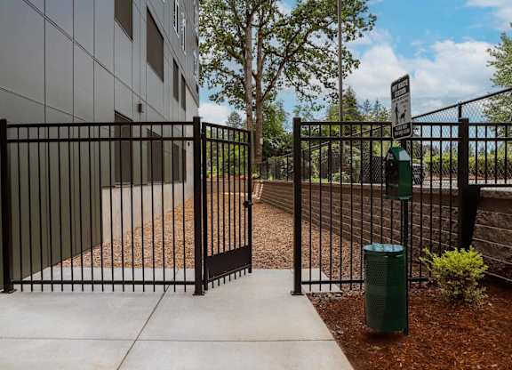 A black gate with a sign on it is in front of a building.