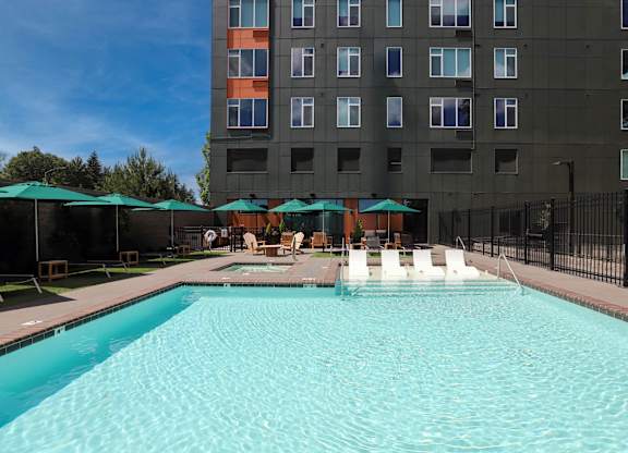 A large swimming pool in front of a tall building.