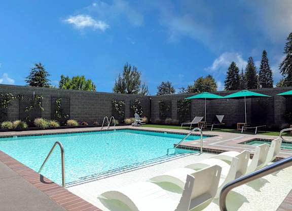 A pool with a metal ladder and white chairs.