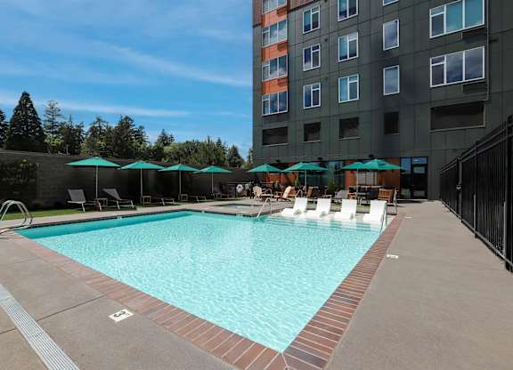 A large swimming pool with a red brick border and a black fence.