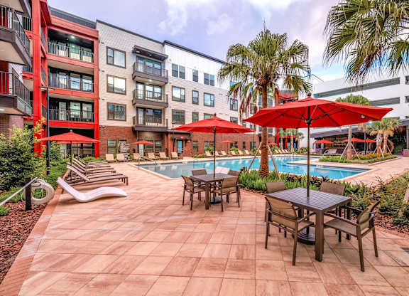 A pool surrounded by chairs and umbrellas in a courtyard.at Parkway Crossings, Kissimmee, FL