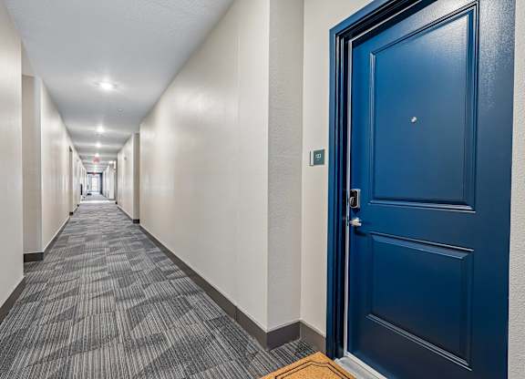 A long hallway with a blue door at the end.