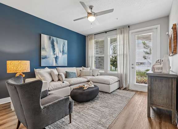 A living room with a grey armchair and a grey ottoman.
