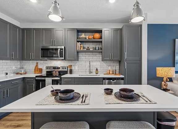 A modern kitchen with a dining table set for two.