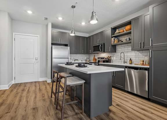 A kitchen with a white countertop and wooden floors.
