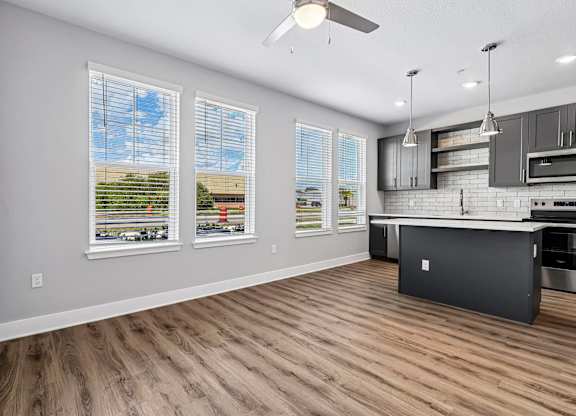 A kitchen with a large island and a view of the outdoors through the windows.