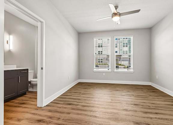 A room with a ceiling fan and wooden flooring.