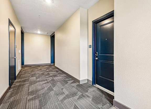 A hallway with a carpeted floor and a blue door.