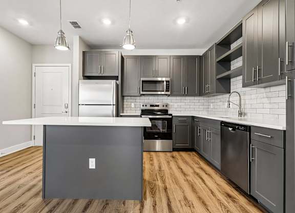 A modern kitchen with stainless steel appliances and wooden floors.