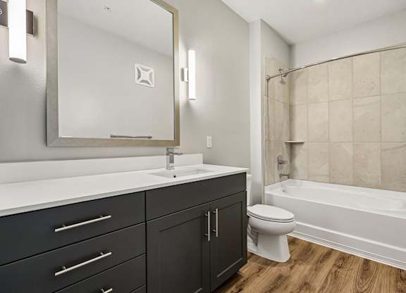 A bathroom with a white sink, black drawers, and a white toilet.