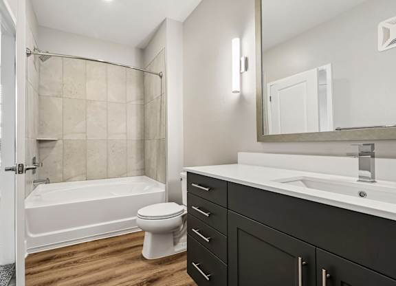 A white toilet sits next to a bathtub in a bathroom.