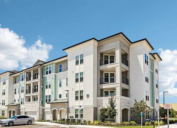 A modern apartment building with a car parked in front.