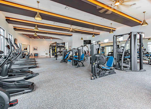 A gym with a variety of equipment including treadmills, weights, and exercise machines.