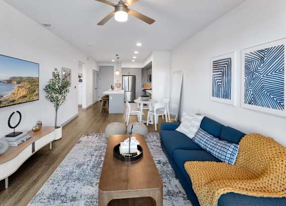 A living room with a blue couch and a painting on the wall.