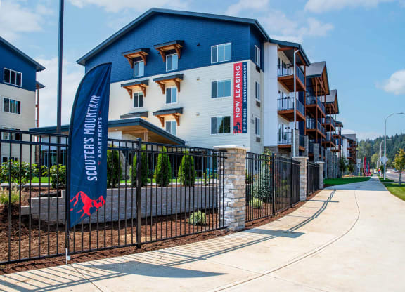 an apartment building with a blue and white facade and a sign on a fenceat Scouter's Mountain, Happy Valley Oregon