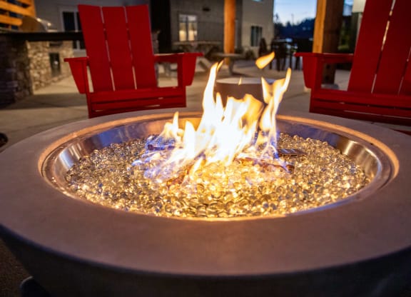 a fire pit in the middle of a patio with red chairsat Scouter's Mountain, Happy Valley Oregon